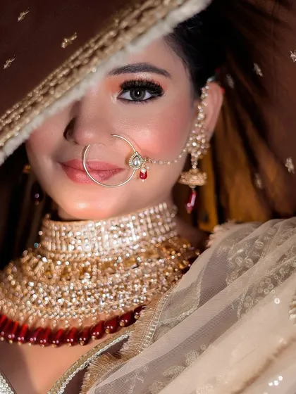 A playful peek-a-boo shot with the dupatta, focusing on the bride's eyes and smile.