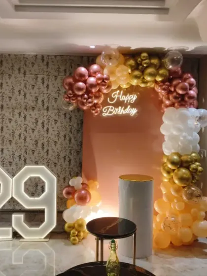 Here’s how I transform a living room into a stylish party space for a 29th birthday. This setup features a modern balloon arch in rose gold and white, a custom backdrop, a neon sign, and a giant light-up number '29'.