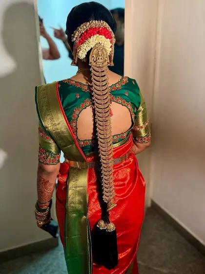 The perfect bridal hairstyle completes the look. Here is a detailed view of a traditional South Indian bridal braid, intricately woven and adorned with a beautiful golden jade, created for Prerna's muhurtham.