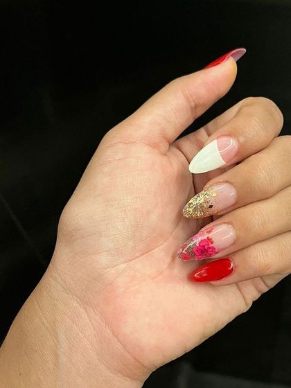 A beautiful example of multi-technique nail art, featuring a French tip, glitter, and delicate floral painting.