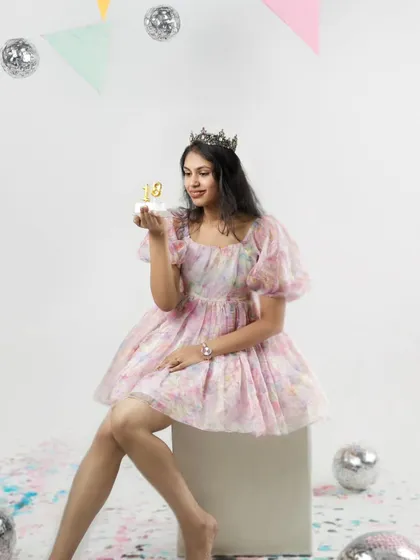 A princess for a day. Wearing a crown and holding a small cake, she looks elegant and happy as she celebrates turning eighteen.