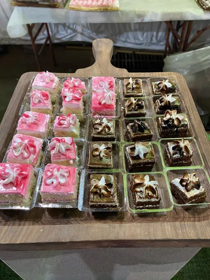 A wooden board displaying an assortment of delicate mini pastries in strawberry and chocolate flavors.
