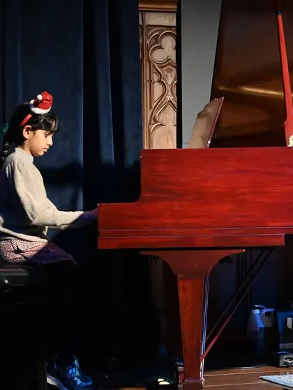 A beautiful shot of a student performing on the grand piano. The experience of playing on a concert-quality instrument is invaluable for aspiring pianists.
