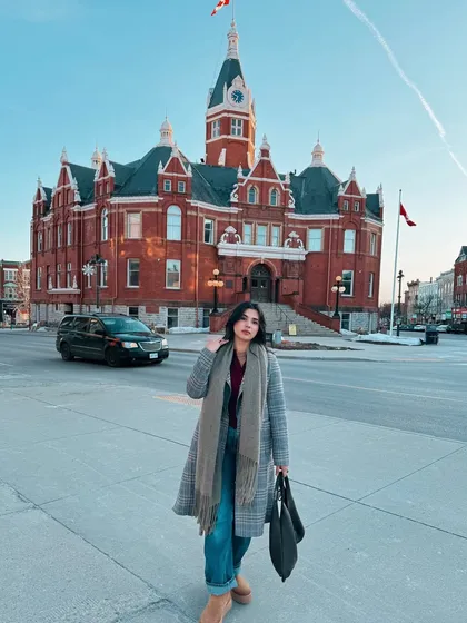 Capturing the winter magic in Stratford, Ontario. This shot shows how I style a cozy but chic winter outfit with a plaid long coat and scarf against a beautiful, historic backdrop.