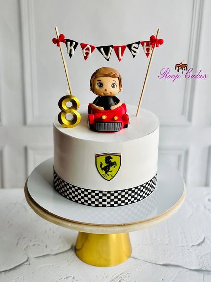 A sleek Ferrari-themed cake for an 8th birthday. The design includes the iconic logo, a checkered flag border, and a handcrafted fondant figure of the birthday boy in his own red sports car.