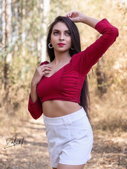 A classic portrait pose set against a beautiful woodland backdrop. The soft, natural light of the golden hour enhances the model's features and the rich colors of her outfit.