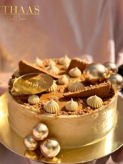 A closer look at my Lotus Biscoff cake. It is adorned with crushed and whole Biscoff cookies, piped frosting, and shimmering golden spheres for a touch of luxury.
