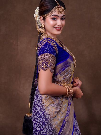 A royal blue and silver brocade saree. The draping here is all about showcasing the richness of the fabric, with a neatly pleated pallu and a full, grand silhouette.