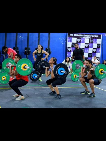 A wide shot of multiple teams performing synchronized front squats during the competition, showcasing the scale and energy of the event.