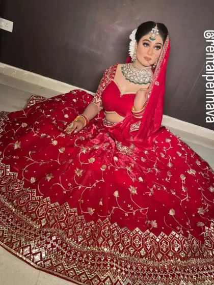 A high-angle shot of a classic red velvet bridal lehenga, highlighting the rich color and the detailed zardozi work on the border.