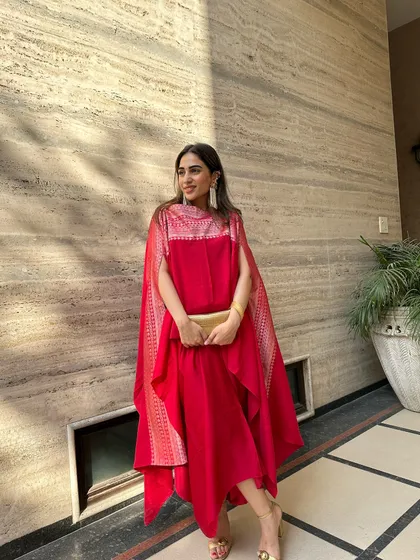 A modern festive look featuring a red cape set from Sobariko. This is perfect for someone who wants a contemporary outfit for a festival or party.