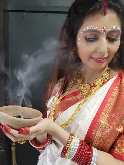The spiritual essence of Durga Puja, captured beautifully. The traditional Bengali saree drape adds to the sanctity of the moment.