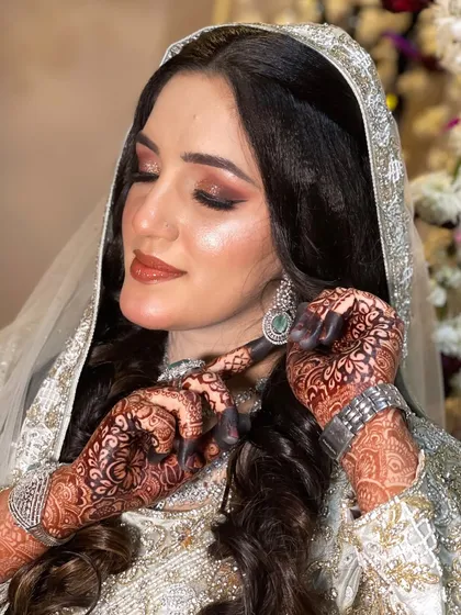 A candid moment showing the bride adjusting her earring, highlighting her intricate henna.