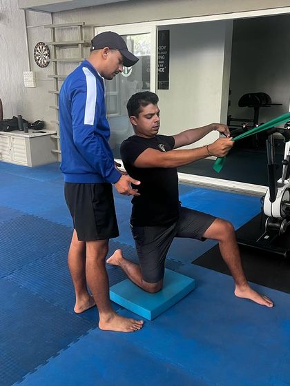 Correct form is paramount to prevent injury and maximize results. A physiotherapist makes a minor adjustment to an athlete's posture during a resistance band exercise.