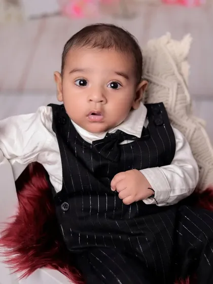 A charming close-up shot. This angle highlights the baby's sweet face and pinstripe outfit, capturing the details of this milestone session.