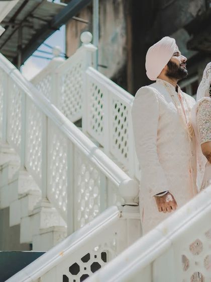 A grand, architectural portrait of a Sikh couple on a white marble staircase, creating a regal and timeless image.