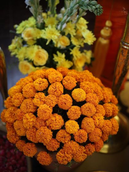 A close-up of a classic marigold floral arrangement. The vibrant orange of the genda phool is a staple in Indian celebrations, bringing warmth and traditional beauty to the decor.