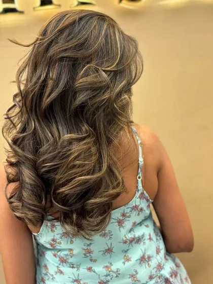 A close-up of the beautiful, multi-tonal highlights in a client's hair, styled to perfection with soft, flowing waves.