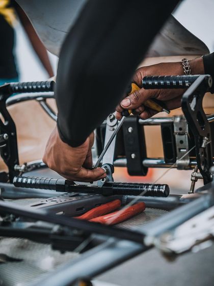 A mechanic making adjustments to a kart's pedals.