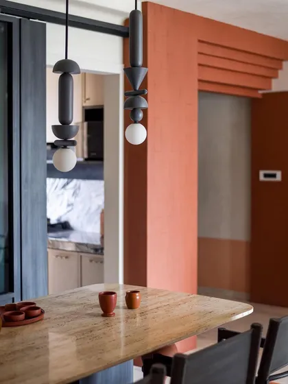 Another view of the dining area, showing the connection to the kitchen through the glass partition. The terracotta pottery on the table ties in with the overall color scheme.