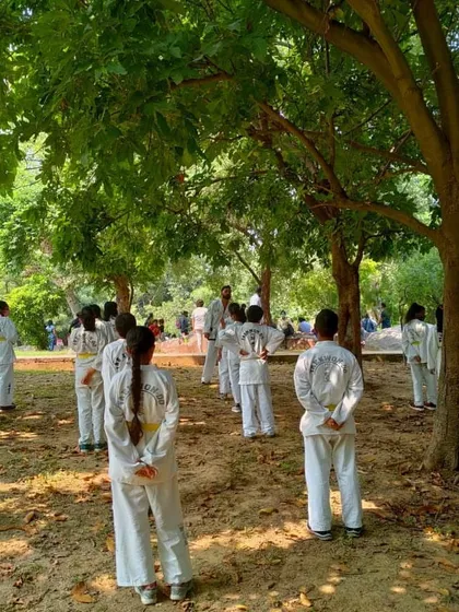 Students standing at ease with hands behind their backs, a sign of respect and discipline in traditional Taekwondo.