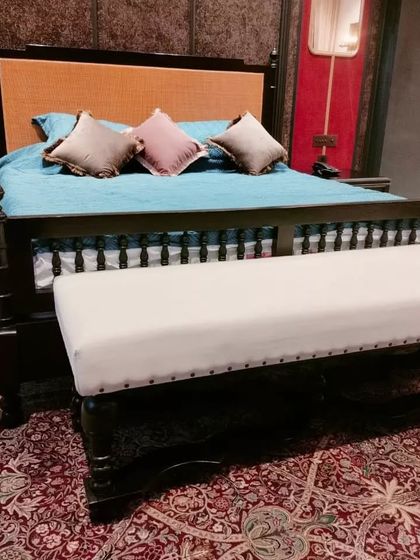 A closer look at the details of the dark wood four-poster bed, including the turned posts and the nailhead trim on the bench.