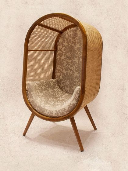 The 'Dome' chair, a unique cocoon design with a teak frame, woven rattan shell, and a patterned fabric interior. It’s a standout piece that offers a private retreat.