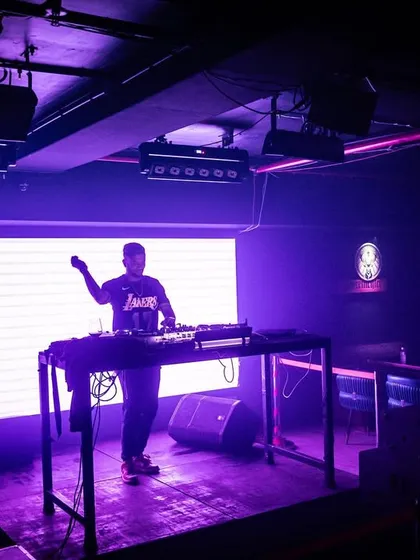 A wide shot of the stage at Cyclone Club, bathed in purple light, creating a cool and moody atmosphere.