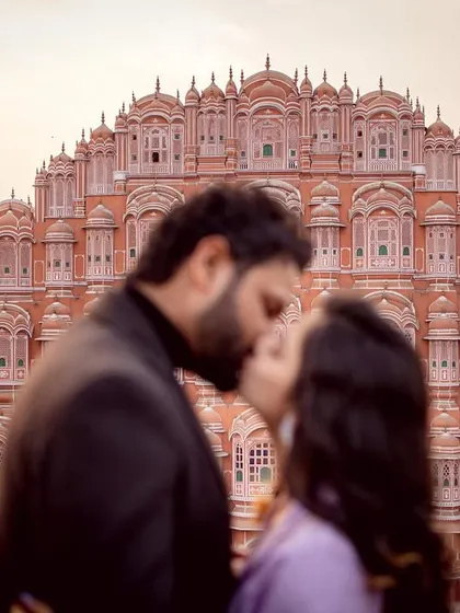 A romantic kiss with the iconic Hawa Mahal in Jaipur as the backdrop. This shot is intentionally blurred to focus on the intimacy of the moment, while still evoking the sense of a grand destination.