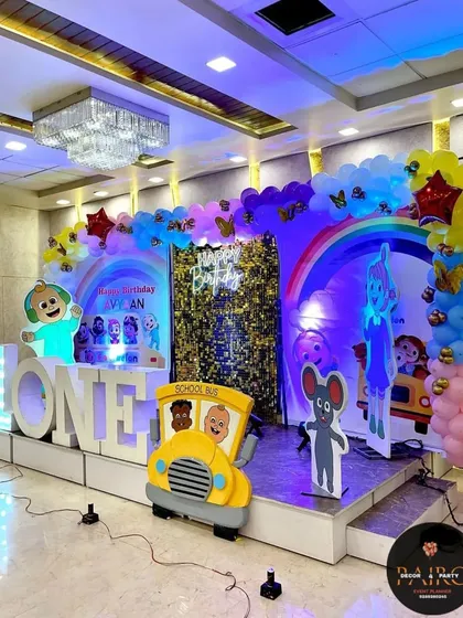 Cocomelon is one of the most requested themes for first birthdays. I designed this complete stage with large character cutouts, a "ONE" marquee, a school bus prop, and a rainbow balloon arch to bring the popular show to life.
