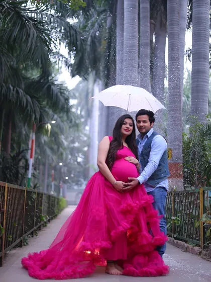 An outdoor maternity photoshoot in a beautiful park setting. I help couples celebrate their pregnancy with vibrant and dramatic portraits like this one, using flowing gowns to create a stunning visual.