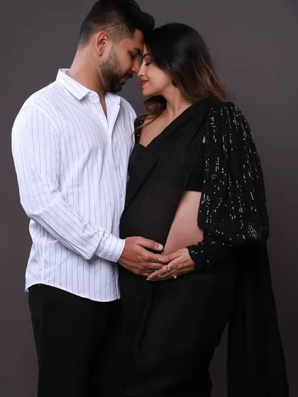 An intimate close-up showing the deep connection between the couple. Dressed in a modern saree and a classic shirt, their pose is full of love and anticipation for their new arrival.