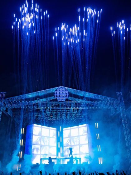 Blue fireworks shoot into the sky above the Dimitri Vegas & Like Mike stage, creating a stunning visual against the night.