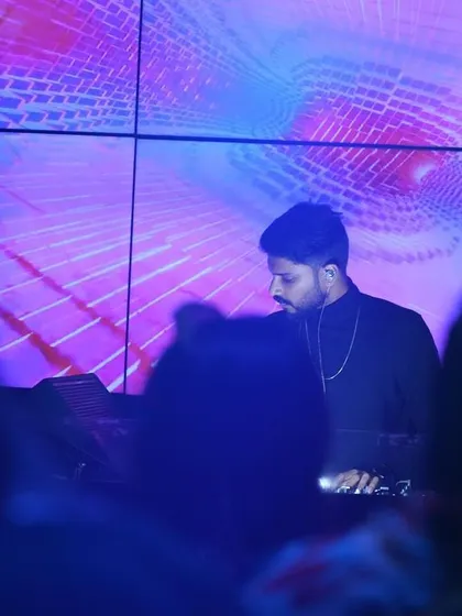 A shot from the crowd's perspective, showing me at the decks against a mesmerizing purple and blue visual display. The goal is to create a complete sensory environment where the music and visuals feel like one.