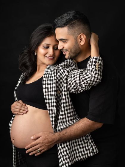 A stylish and intimate portrait of the parents-to-be. Her modern houndstooth blazer and his simple black shirt create a fashionable, coordinated look for their studio maternity session.