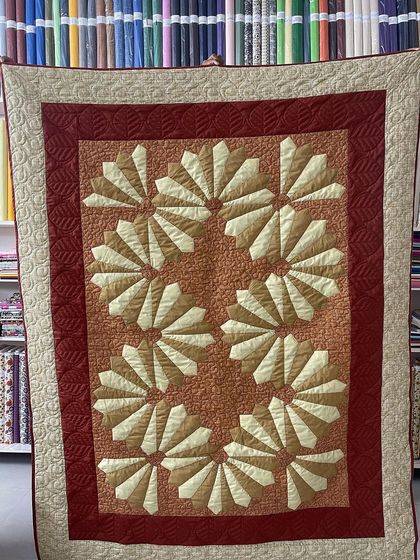 A Dresden Plate quilt in warm, earthy tones of red and beige.