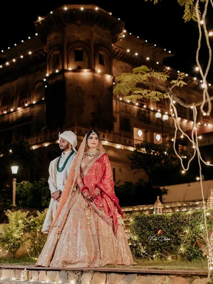 A regal portrait of Dheemant and Geet against the backdrop of their illuminated wedding palace. We use the venue's beauty to create stunning, atmospheric night shots.