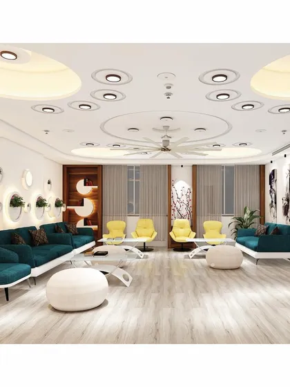 The spacious waiting lounge at SVG Exports, designed for comfort and style. The area features modern teal sofas, contrasting yellow armchairs, and unique wall-mounted planters, all under an intricate ceiling with recessed lighting.