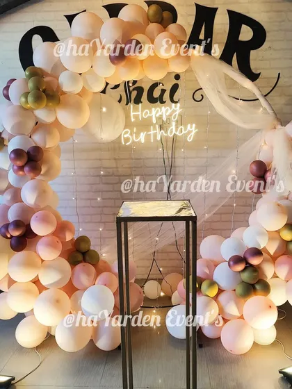 A beautiful pastel balloon ring in a restaurant, using a sheer drape and fairy lights to soften the look.
