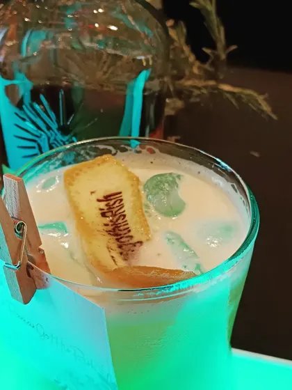 A creamy cocktail with a custom-branded biscuit garnish, showcasing our creative and personalized approach to drinks.