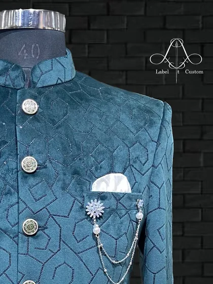 A close-up of a one-of-a-kind velvet Bandhgala in a stunning teal. The geometric pattern and custom brooch make this a truly special piece for any occasion.
