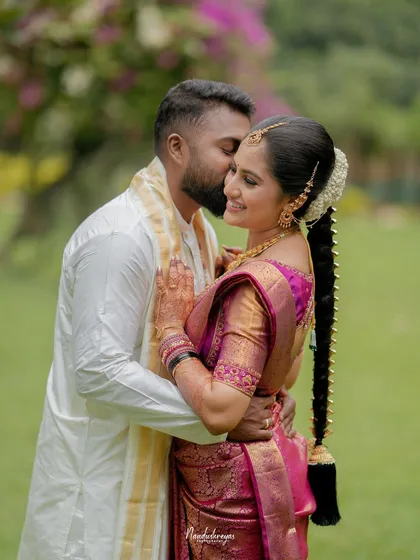 A tender kiss on the cheek, this intimate close-up in a garden setting highlights the affection and warmth between the couple.