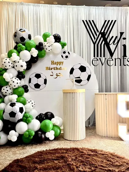 A football-themed birthday party for a 5-year-old, with a green, black, and white balloon arrangement and football details.