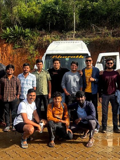 A group poses with their tempo traveler, ready to head out. The journey starts here.