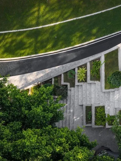 An aerial view of the landscape design for Villa KD 45, showing the interplay of curved pathways, terraced planters, and lush green lawns that complement the architecture.