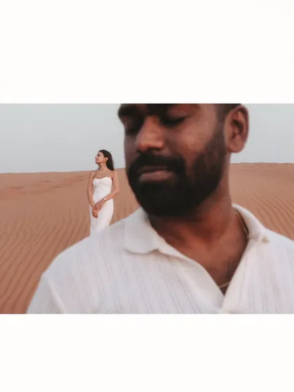 An artistic shot using depth of field to create a narrative. The groom is in soft focus in the foreground, his thoughts seemingly on his bride standing elegantly in the distance.
