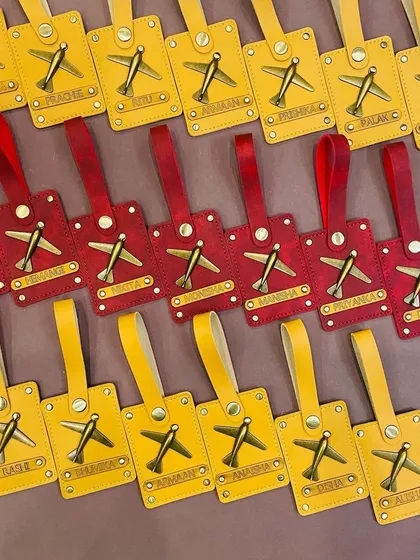 A closer look at our red and yellow personalised luggage tags. The antique brass airplane charm adds a vintage touch.