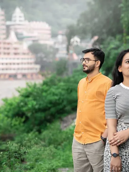 Looking out at the view, with the iconic Tera Manzil Temple in the background. This shot connects the couple to the famous landmarks and stunning scenery of Rishikesh.