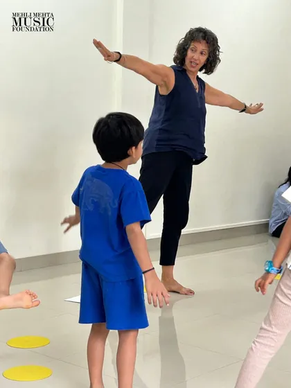 An instructor uses expressive movements to teach musical concepts. Our teachers are trained to create a dynamic and interactive learning environment where children learn by doing.
