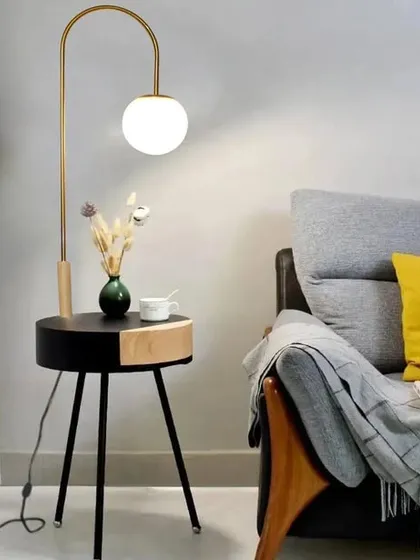This sporadic floor lamp combines an antique brass arch with a black and wood side table. The multifunctional design is perfect for a reading nook, providing light and a convenient surface in one stylish piece.